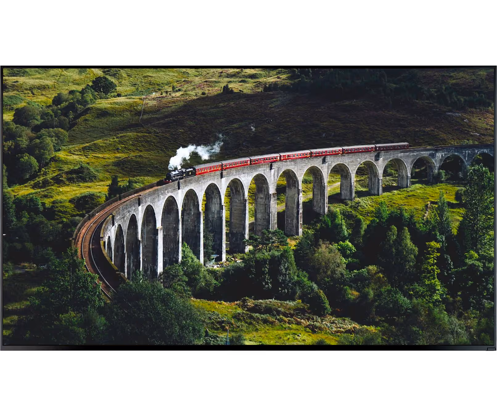 Steam train with red carriages crossing a curved stone viaduct over green hills and trees.